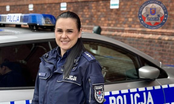 Umundurowana policjantka stoi przy radiowozie.