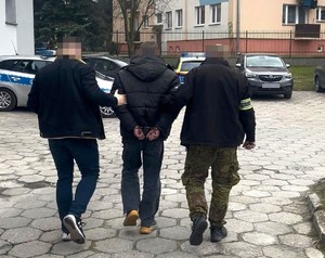 Dwaj policjanci prowadza zatrzymanego.