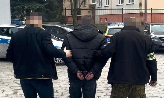 Dwaj policjanci prowadza zatrzymanego.