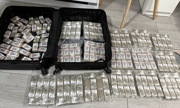 Na podłodze leżą woreczki z porcjami narkotyków, Obok torba podróżna, w której również znajdują się narkotyki.