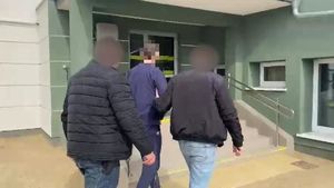 Dwaj nieumundurowani policjanci prowadzą do budynku zatrzymanego.