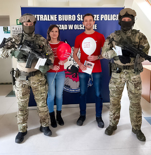 Dwaj umundurowani funkcjonariusze oraz mężczyzna i kobieta.