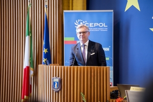Mężczyzna przemawia do zgromadzonych stojąc przy mównicy.