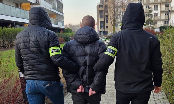 Dwoje funkcjonariuszy prowadzi zatrzymanego.