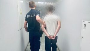 Policjant prowadzi korytarzem zatrzymanego.