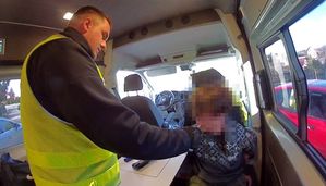 policjant siedzi w radiowozie z zatrzymanym.