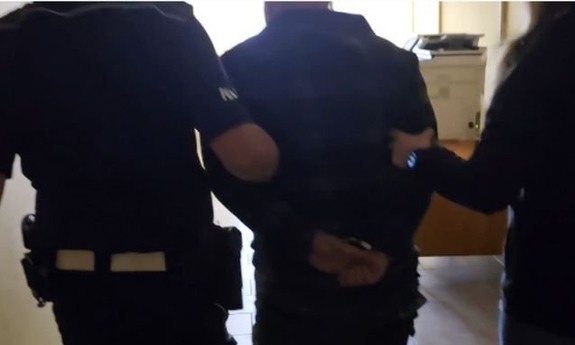 Zatrzymany prowadzony przez dwóch policjantów.