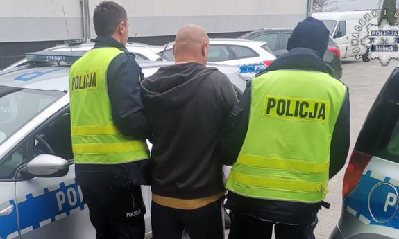 policjanci idą z zatrzymanym.