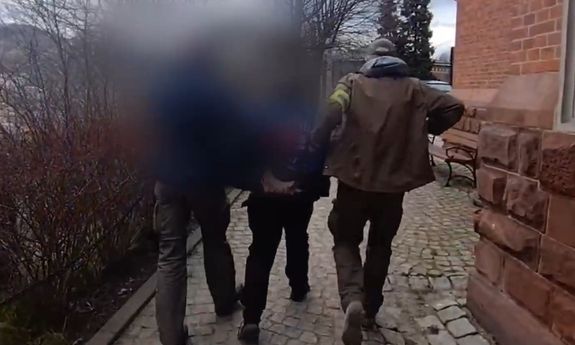 dwóch policjantów idzie z zatrzymanym.