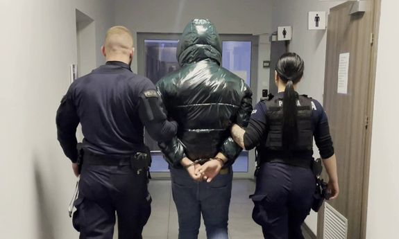 dwóch policjantów idzie z zatrzymanym.