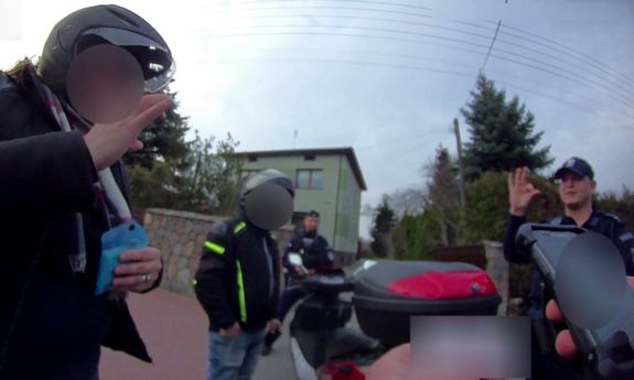 Kadr z nagrania. Policjant porozumiewa się z kobietą za pomocą języka migowego.
