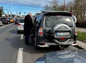 Policjant po cywilnemu stoi w drzwiach kierowcy samochodu marki Pajero.