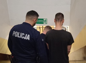 Dwaj policjanci prowadzą zatrzymanego.