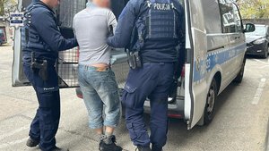policjanci prowadzą zatrzymanego.