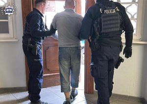 policjanci prowadzą zatrzymanego.