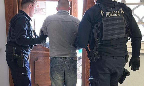 policjanci prowadzą zatrzymanego.