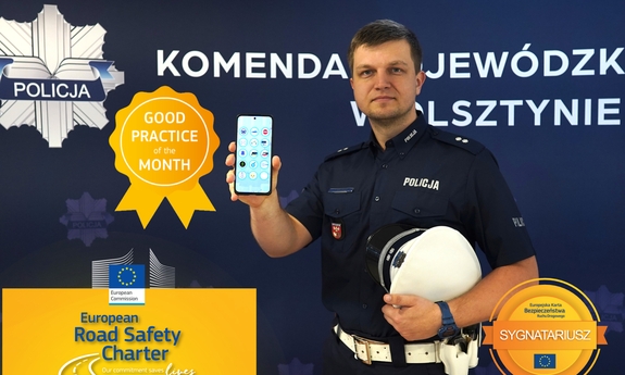 Na zdjęciu umundurowany funkcjonariusz trzyma w dłoni telefon komórkowy. Na telefonie wyświetlana jest aplikacja.