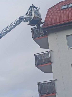 policjant na wysięgniku sięga do balkonu.