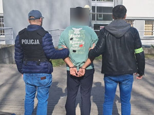 policjanci stoją z zatrzymanym.