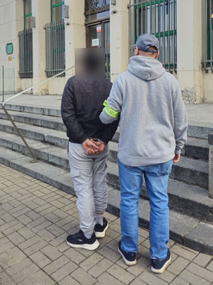 policjanci stoją z zatrzymanym.