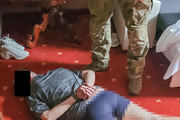 Zatrzymany leży na podłodze, a obok widać nogi stojącego przy nim policjanta.