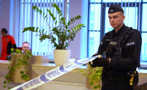 Umundurowany policjant rozwija taśmę z napisem Policja.