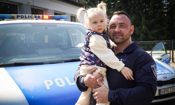 Policjant trzyma dziewczynę na rękach.