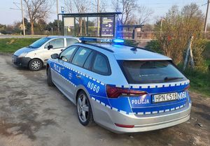 Radiowóz stoi obok zatrzymanego pojazdu.