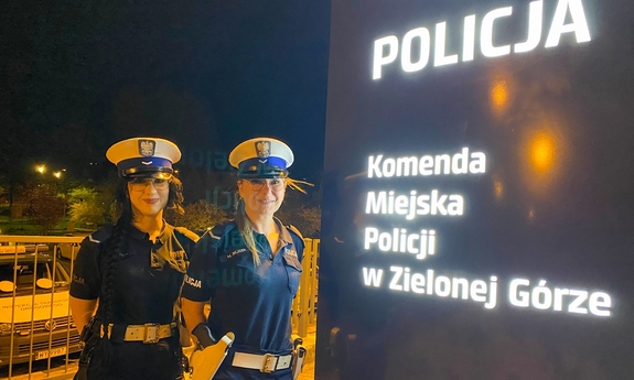 Dwie policjantki stoją przy pylonie informacyjnym z napisem Komenda Miejska Policji w Zielonej Górze.