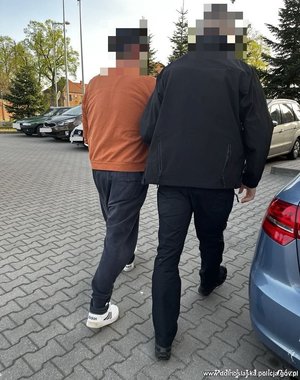policjant idzie z zatrzymanym.
