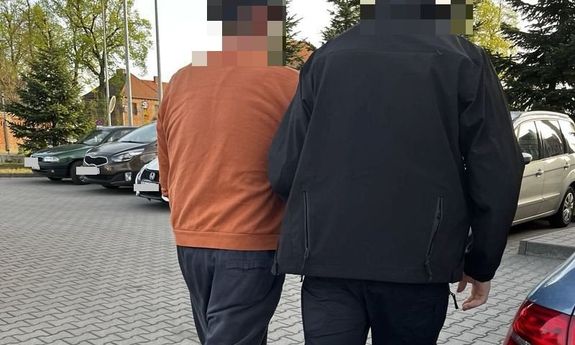policjant idzie z zatrzymanym.