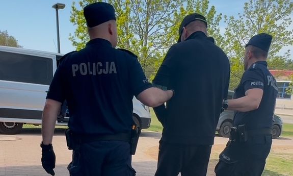 policjanci idą z zatrzymanym.