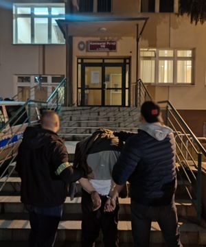 Policjanci z zatrzymanym mężczyzną zakutym w kajdanki.