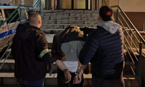 Policjanci z zatrzymanym mężczyzną zakutym w kajdanki.