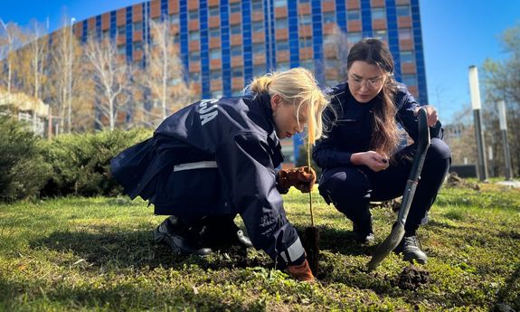 Dwie umundurowane policjantki sadzą drzewo.