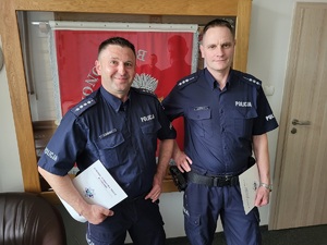 Dwaj umundurowani policjanci pozują do zdjęcia.