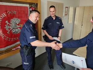 Umundurowani policjanci ściskają sobie ręce.
