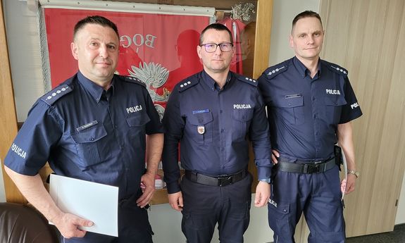 Trzej umundurowani policjanci pozują do zdjęcia.