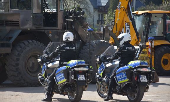 Policjanci na motocyklach. W tle koparki.