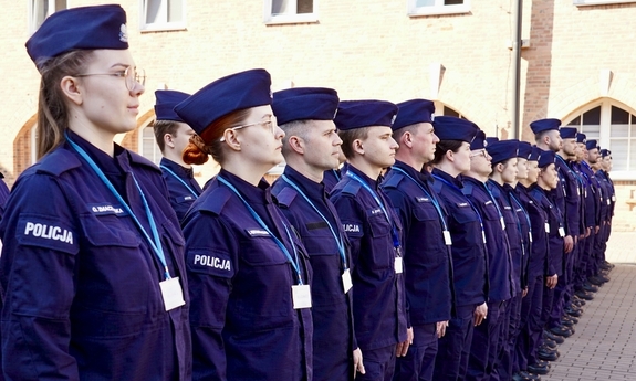 Na zdjęciu umundurowane policjantki i umundurowani policjanci stoją w szeregu.