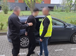 Policjanci z zatrzymanym zakutym w kajdanki.