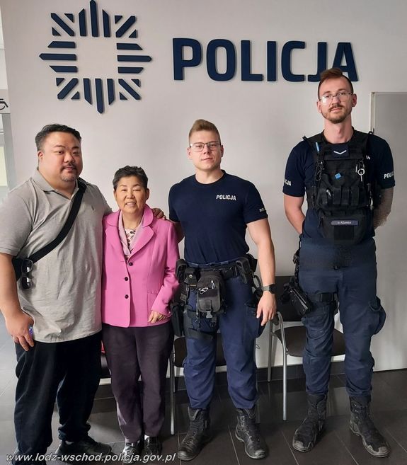 Cztery osoby stoją przy ściance z napisem Policja. Dwie osoby ubrane po cywilnemu i dwóch umundurowanych policjantów.