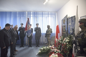 Na zdjęciu dwóch mężczyzn oddaje hołd poległemu policjantowi.