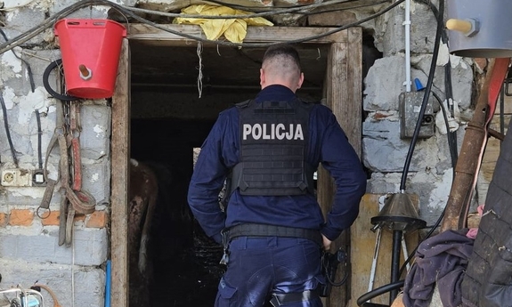 Policjant wchodzący do pomieszczeń gospodarczych.