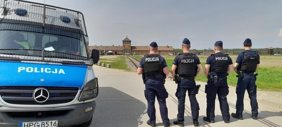 Policjanci przy radiowozie w tle Brama Śmierci w Brzezince.