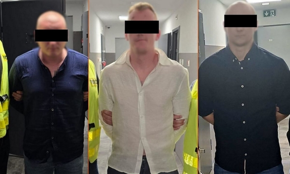 Dwaj policjanci z zatrzymanym mężczyzną zakutym w kajdanki.