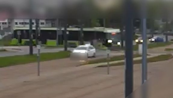 kadr z monitoringu. biały samochód jedzie po torowisku, za nim stoi tramwaj.