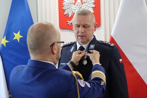 Paweł Błasiak przypina medal dyrektorowi Biura Prewencji insp. Robertowi Kumorowi.
