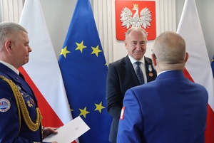 Paweł Błasiak gratuluje mężczyźnie po wręczeniu mu medalu.