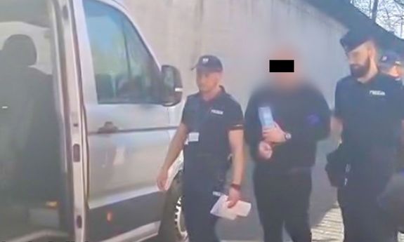 policjanci idą z zatrzymanym.